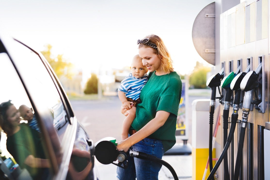 Frau mit Kind tankt an einer Tankstelle ihr Auto